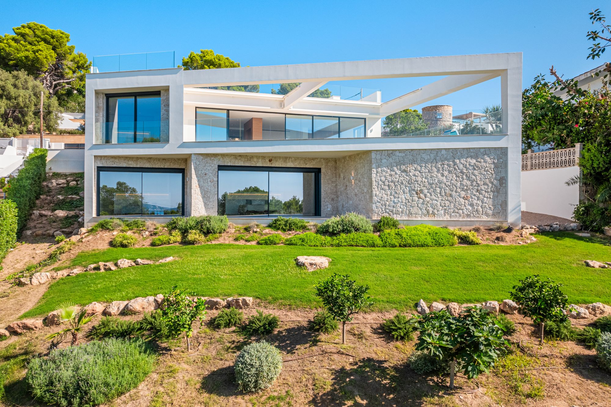 DJI_0644_HIGH "An image of a sleek designer home with breathtaking views. The house features contemporary architecture with clean lines, large glass windows, and a minimalist aesthetic. The interior opens seamlessly to an outdoor terrace, where stylish furnishings invite relaxation. Beyond, panoramic views of rolling hills, a sparkling coastline, or a vibrant cityscape stretch into the distance, creating a harmonious blend of luxury and natural beauty."